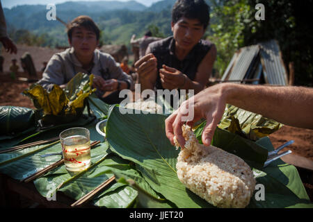 Robert Hahn sert lui-même pour le riz collant pendant le déjeuner sur un site de construction pour une maison neuve à Ban Phak Kung, le Laos. De nombreux membres de la communauté viennent aider et sont a remercié avec un repas. Banque D'Images