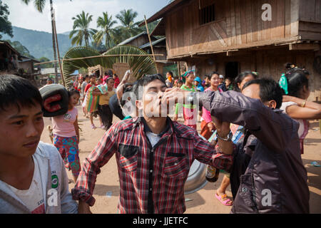Un homme est offert un shot de Lao-lao (whisky de riz) à une procession de mariage à Muang Hat Hin, au Laos. Banque D'Images