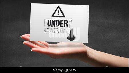 Digital composite de la main avec la carte montrant la construction gris doodle contre mur gris Banque D'Images