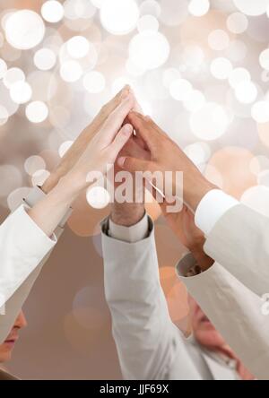 Digital composite de mains de teamk ensemble d'atteindre avec l'arrière-plan flou léger pétillant Banque D'Images