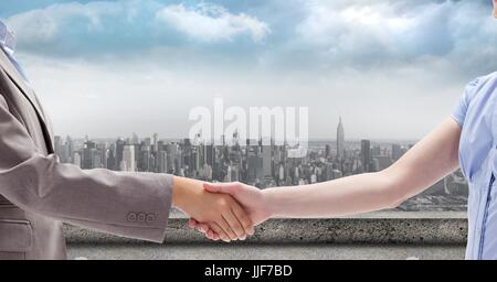 Digital composite de l'image recadrée de businessman and businesswoman shaking hands contre ville Banque D'Images
