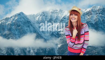 Digital composite of Portrait of smiling hipster debout contre les montagnes aux sommets enneigés Banque D'Images