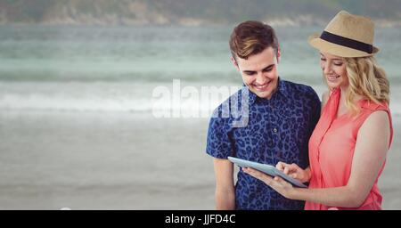 Digital composite de l'homme et de la femme à la mode avec tablet contre plage floue Banque D'Images