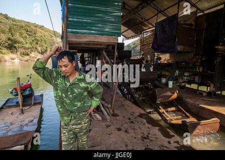 Les hommes vietnamiens exploiter une drague mécanique flottant sur la rivière Nam Ou, au Laos. Six hommes vivent sur le navire pendant des mois, en faisant tourner tout au long de la journée et de travailler en paires pour maintenir la machine en fonctionnement constant. Banque D'Images