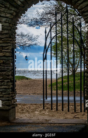 Les portes d'accès à la plage avec un kite surfer sur l'arrière-plan Banque D'Images