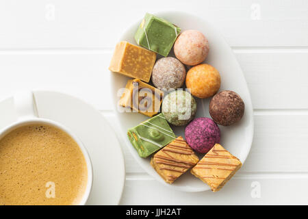 Divers bonbons sucrés et tasse de café avec du café. Banque D'Images