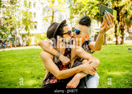 Un couple gay, en tenant vos autoportraits dans un parc à Londres. Banque D'Images