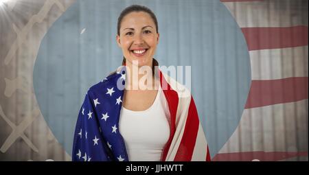 Femme enveloppée dans un drapeau américain contre le panneau de bois floue avec le drapeau américain à la main et l'arrondi Banque D'Images