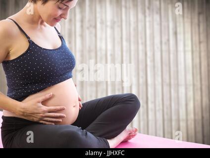 Pregnant woman meditating contre panneau floue Banque D'Images