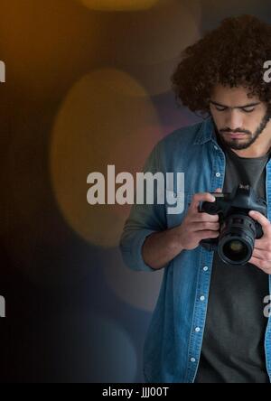 Le photographe à la recherche d'images sur l'appareil photo. Feux jaune floue autour de lui Banque D'Images