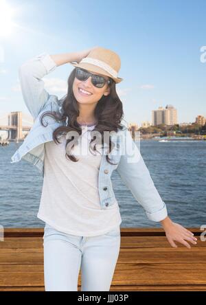 Woman with hand on summer hat contre l'eau et les toits avec flare Banque D'Images