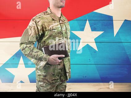 Vue latérale du soldat tenant un livre en face de drapeau américain Banque D'Images