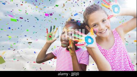 Les filles avec de la peinture sur les mains contre ciel avec flare et confettis Banque D'Images