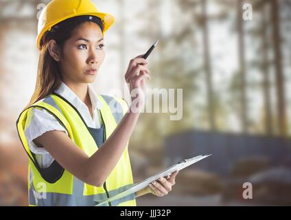 Femme builder avec presse-papiers contre chantier floue Banque D'Images