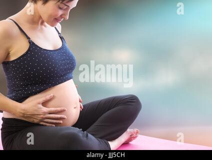Pregnant woman meditating contre floue fond marron bleu Banque D'Images