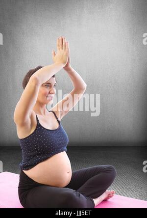 Pregnant woman meditating in grey room Banque D'Images