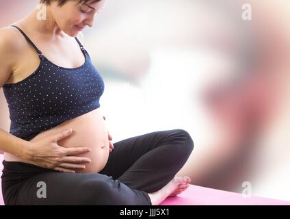 Pregnant woman meditating contre rouge et blanc floue abstract background Banque D'Images