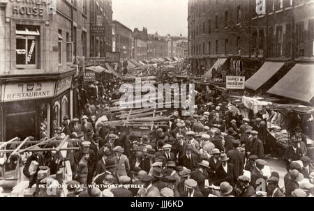 Marché Petticoat Lane, Wentworth Street, London au début des années 1900. Quartier juif, de nouveaux immigrants de l'Europe de l'Est.. Les hommes portaient tous des Casquettes et chapeaux. L'écriture Hébraïque - restaurant cacher. East End. Banque D'Images