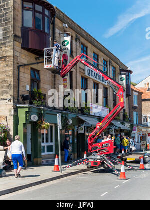 Un décorateur à l'aide d'une plate-forme d'accès hydraulique pour peindre l'extérieur d'un café à Whitby Banque D'Images