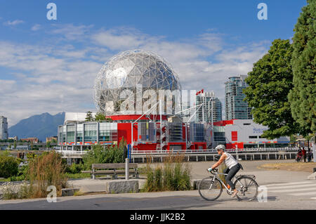 Woman riding bicycle avec TELUS World of Science dome de retour au village sur False Creek, Vancouver, British Columbia, Canada Banque D'Images