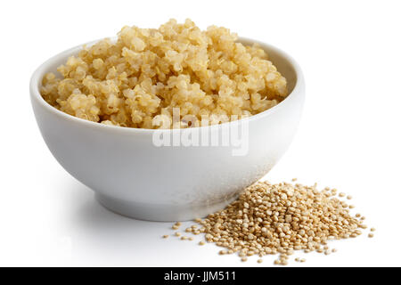 Le quinoa cuit dans un bol en céramique blanc isolé sur blanc. Le quinoa crus renversé. Banque D'Images