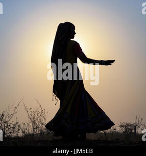 Une gitane danser devant le soleil couchant, Pushkar Camel Fair, Pushkar, Rajasthan, India Banque D'Images