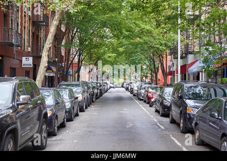 NEW YORK - 28 septembre 2016 : rue étroite à Greenwich Village à Manhattan, avec des voitures garées des deux côtés sous un toit de feuilles vertes Banque D'Images