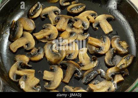 Champignons blancs tranchés sautés dans une poêle en fonte Banque D'Images