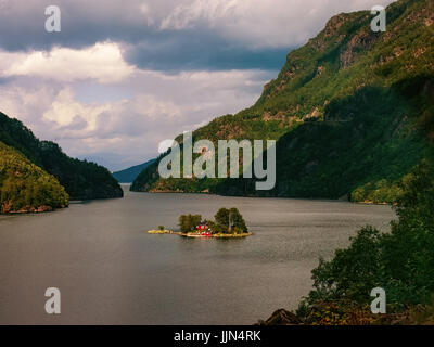 Vue de la nature du Nord - ciel dramatique au-dessus de montagnes et une petite île entre l'eau d'un fjord norvégien. Banque D'Images