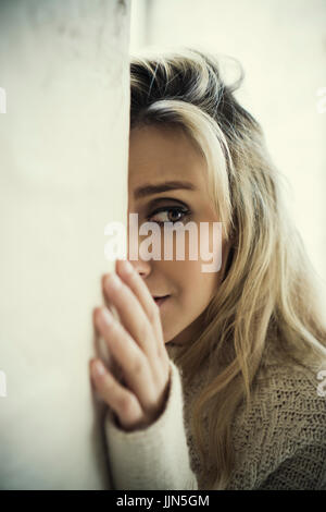 Jeune femme peur de se cacher derrière un mur à l'écart de pleurer Banque D'Images
