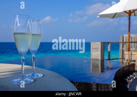 Une paire de verres de champagne sont fixés au bord de la piscine, pour un couple de profiter de leur terrasse privée dans un Luxueux resort aux Maldives. Banque D'Images