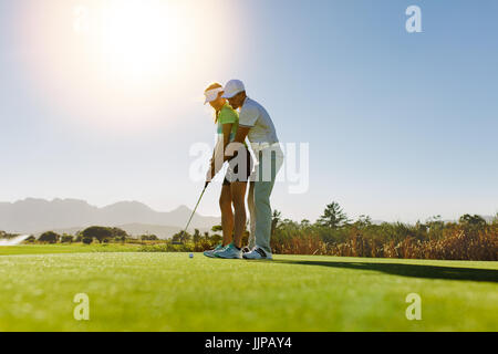 L'enseignement de l'homme femme à jouer au golf en se tenant sur le terrain. Entraîneur personnel donnant sur Leçon de golf. Banque D'Images