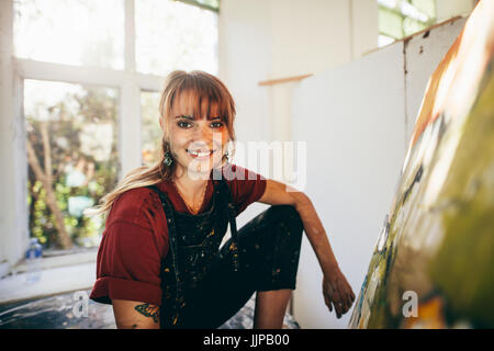 Tourné à l'intérieur du peintre professionnelle en studio. Femme artiste de faire une peinture sur toile dans son atelier. Banque D'Images