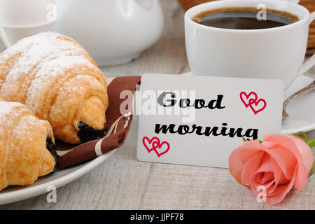 Le petit-déjeuner composé de croissants garniture au chocolat tasse de café le matin et une carte avec un souhait bonjour. Banque D'Images