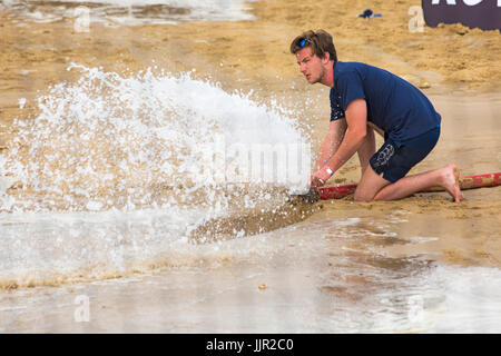 On arrose le sable pour l'organisme de bienfaisance course entre une Porsche et le cheval sur la plage au British Beach Polo Championships à Poole, Sandbanks en Juillet Banque D'Images