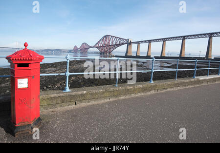 Post box rouge à South Queensferry avec l'emblématique pont du Forth à l'arrière-plan. Banque D'Images