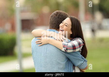 Heureuse rencontre de deux friends hugging outdoors in a park Banque D'Images