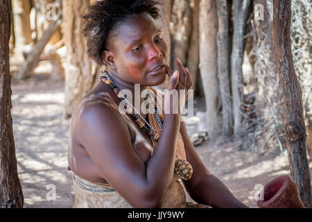 Damara femme assise à l'ombre peinture ses joues au Damara musée vivant, la Namibie, l'Afrique. Banque D'Images