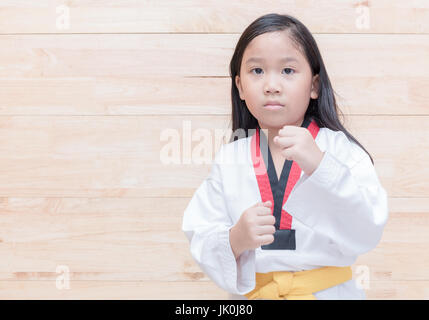 Taekwondo asiatique fille sur acton sur fond de bois, le sport et la santé concept Banque D'Images