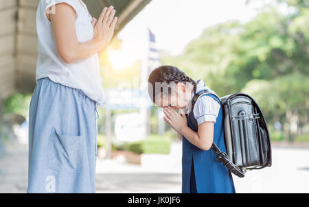 Cute girl student payer l'égard de sa mère avant d'aller à l'école.La culture thaïlandaise Banque D'Images