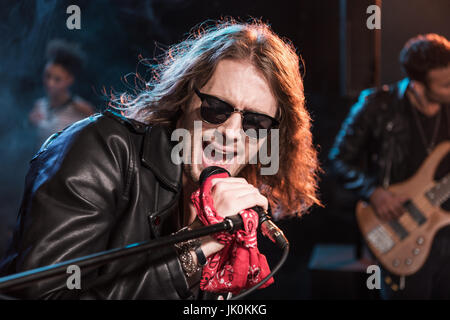 Chanteur avec microphone et rock and roll groupe jouant de la musique hard rock sur scène Banque D'Images