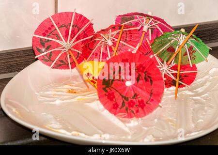 Plaque de gâteau blanc vide, la plaque sur une plaque avec du papier de cuisine colorée décoration parapluie. Banque D'Images