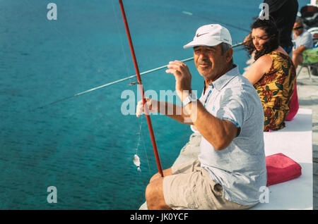 Pefkohori, Grèce - 26 mai 2015 : l'homme portant une casquette montre ses prises durant la saison de pêche dans la mer Égée Banque D'Images