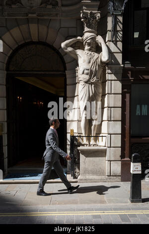 Un homme passe devant un Atlantes figure par le sculpteur H.A. Pegram (1896) à l'entrée de Drapers' Hall livery company à Throgmorton Street, le 17 juillet 2017, dans la ville de Londres, en Angleterre. Les tabliers' Company est une société livrée dans la ville de Londres dont les racines remontent au 13ème siècle, lorsque comme son nom l'indique, il a été impliqué dans le commerce de draperie. Bien qu'il n'est plus impliquée dans le commerce, l'entreprise a évolué l'acquisition d'une nouvelle pertinence. Son rôle principal aujourd'hui est d'être le fiduciaire du fonds de bienfaisance qui ont été laissées dans son soin au cours des siècles. La société a également Banque D'Images