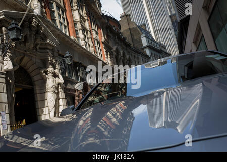 L'architecture des tours et de tabliers' Hall y compris les chiffres des Atlantes par le sculpteur H.A. Pegram, reflétée dans le capot d'une voiture stationnée à Throgmorton Street, le 17 juillet 2017, dans la ville de Londres, en Angleterre. Les tabliers' Company est une société livrée dans la ville de Londres dont les racines remontent au 13ème siècle, lorsque comme son nom l'indique, il a été impliqué dans le commerce de draperie. Bien qu'il n'est plus impliquée dans le commerce, l'entreprise a évolué l'acquisition d'une nouvelle pertinence. Son rôle principal aujourd'hui est d'être le fiduciaire du fonds de bienfaisance qui ont été laissées dans son soin au cours des siècles. Les co Banque D'Images