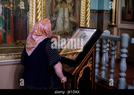 Une femme russe âgée prie devant une icône religieuse à l'intérieur de l'église orthodoxe Uspenskiy Sobor dans la ville de Biysk dans la région d'Altai Krai en Sibérie occidentale, Russie Banque D'Images