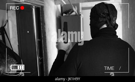 Caméra de surveillance a enregistré le voleur,qui ont fait irruption dans la chambre avec une arme,portant un sac avec le butin. Banque D'Images