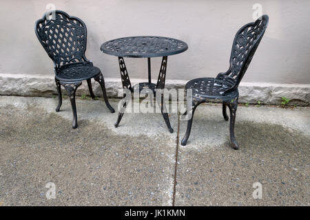 Fonte noire table et chaises à l'extérieur sol humide. Banque D'Images