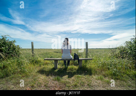 Femme assise sur un banc en bois, enoying la vue dans la campagne Banque D'Images