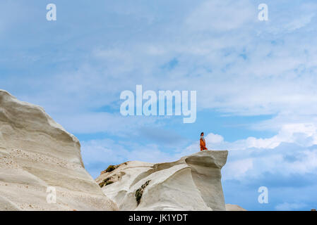 Milos, Grèce, le 17 mai 2017 : young woman standing touristique sur un rocher et regardant belle plage de Sarakiniko. Île de Milos, en Grèce. Banque D'Images